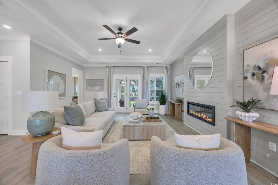 Living area featuring light wood finished floors, a fireplace, recessed lighting, a tray ceiling, and ceiling fan