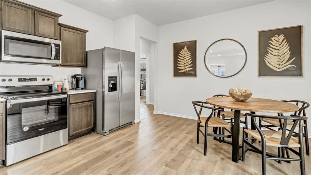 Kitchen with stainless steel appliances, light countertops, dark wood finish cabinetry, and light wood finished floors Kitchen with stainless steel appliances, light countertops, dark wood finish cabinetry, and light wood finished floors