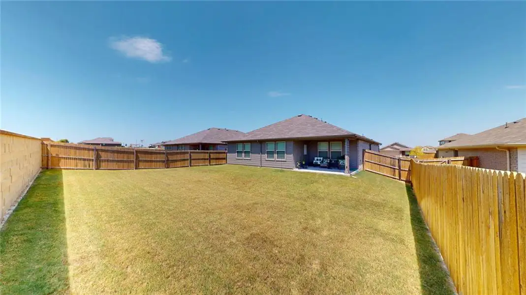 Expansive grassy yard with a wooden privacy fence