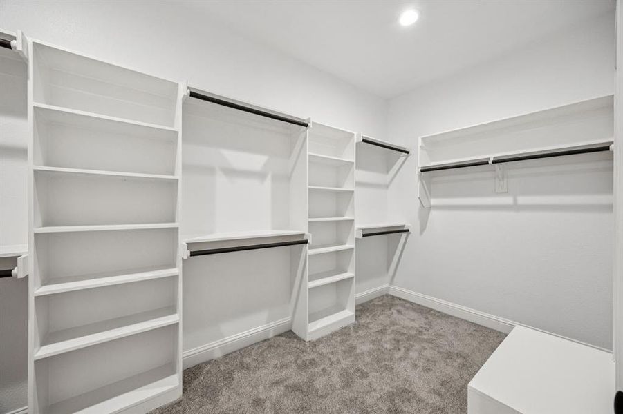 (Bedroom #1) Master bedroom Walk in closet with light colored carpet & built-in shelving.