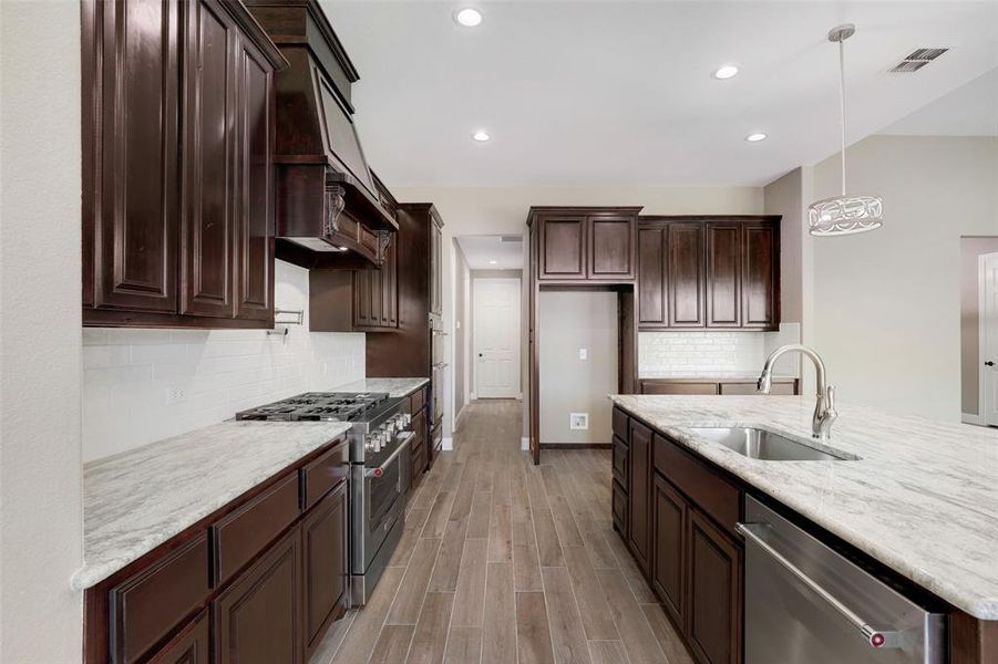 Kitchen with sink, decorative light fixtures, decorative backsplash, and stainless steel appliances