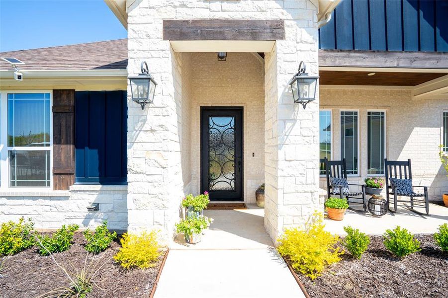 Property entrance featuring stone siding, a porch, and a shingled roof