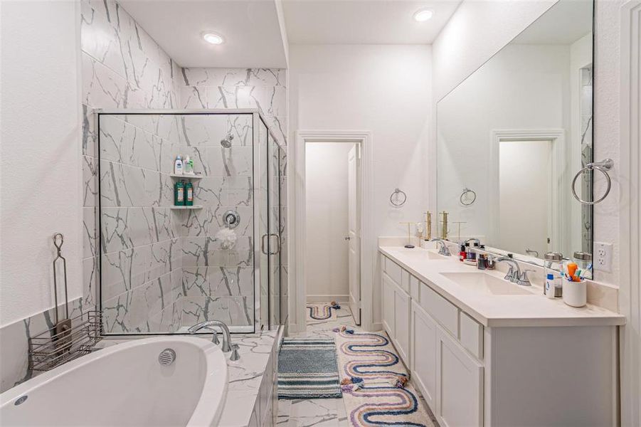 Full bath with a marble finish shower, a bath, and double vanity