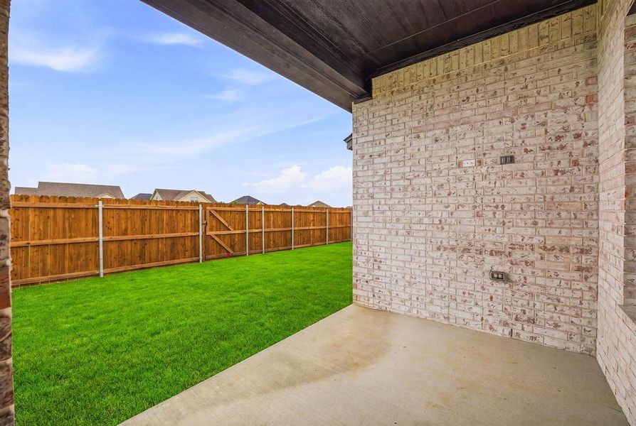 The property features a concrete patio area and a fenced yard with a green lawn