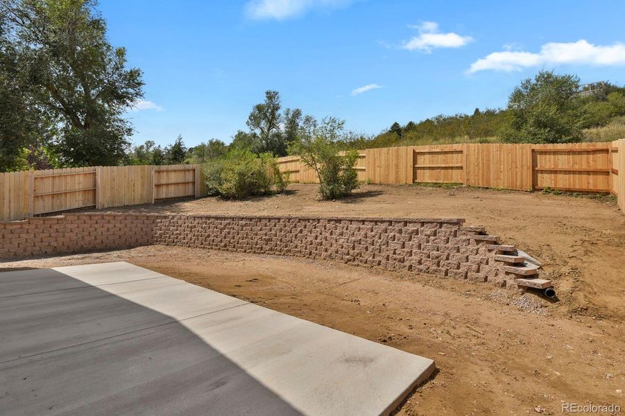 Spacious concrete patio, retaining walls, and rear fencing Spacious concrete patio, retaining walls, and rear fencing