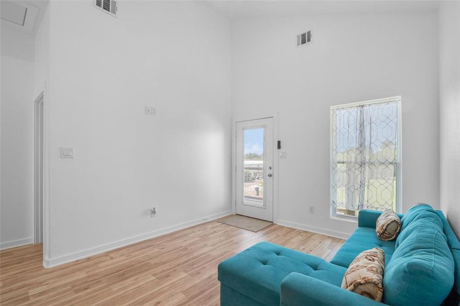 This is a view from the kitchen bar to the front entrance, showing the high-ceiling, clean and contemporary.