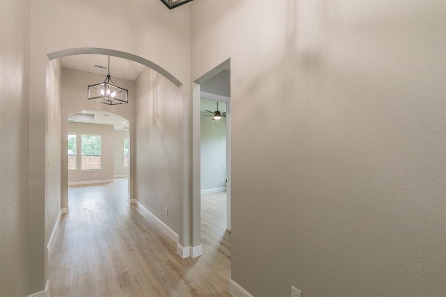 Hall featuring arched walkways, light wood-type flooring, and baseboards Hall featuring arched walkways, light wood-type flooring, and baseboards
