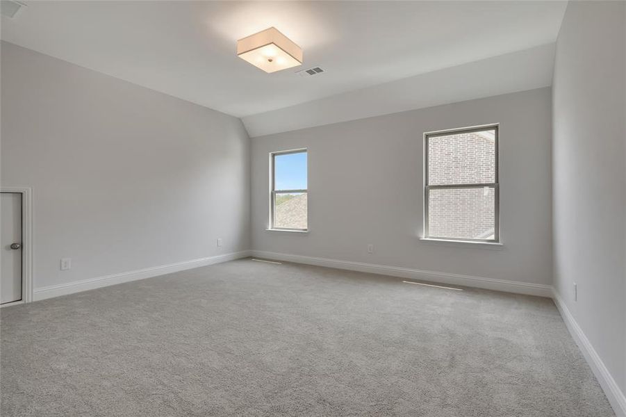 Carpeted spare room with vaulted ceiling