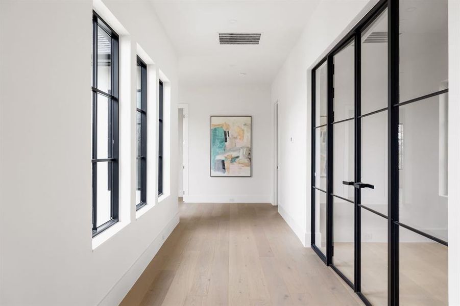 Hallway with light wood-type flooring, plenty of natural light, visible vents, and baseboards