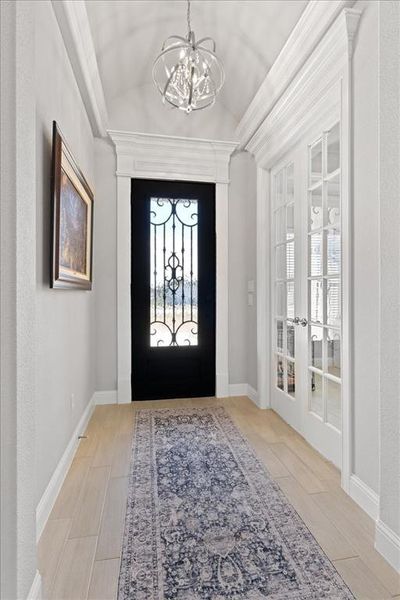 Entryway featuring french doors, an inviting chandelier, wood tiled floor, vaulted ceiling, and baseboards