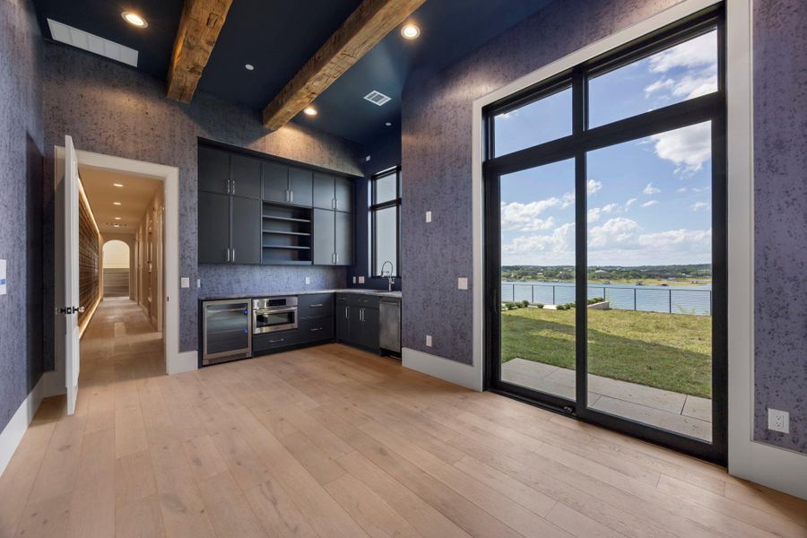 Exposed wood beams crown this elegant space, featuring a compact kitchen with a lake view. Exposed wood beams crown this elegant space, featuring a compact kitchen with a lake view.