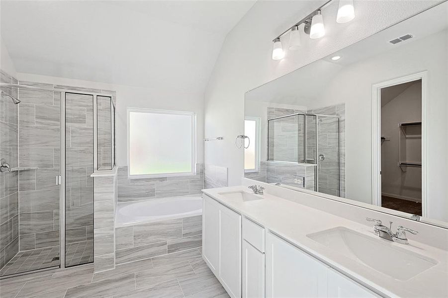 Bathroom featuring vanity, separate shower and tub, and vaulted ceiling