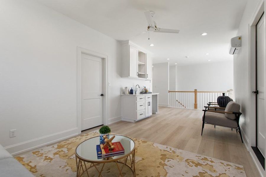 Living area featuring light wood-style flooring, recessed lighting, an upstairs landing, ceiling fan, and a wall unit AC