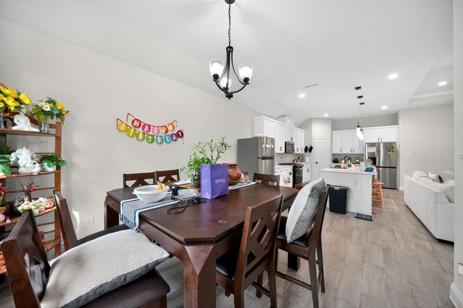 Dining room with light wood-style floors, a chandelier, and recessed lighting
