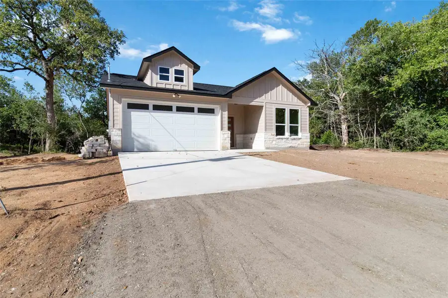 View of front of home with driveway, stone siding, and board and batten siding View of front of home with driveway, stone siding, and board and batten siding
