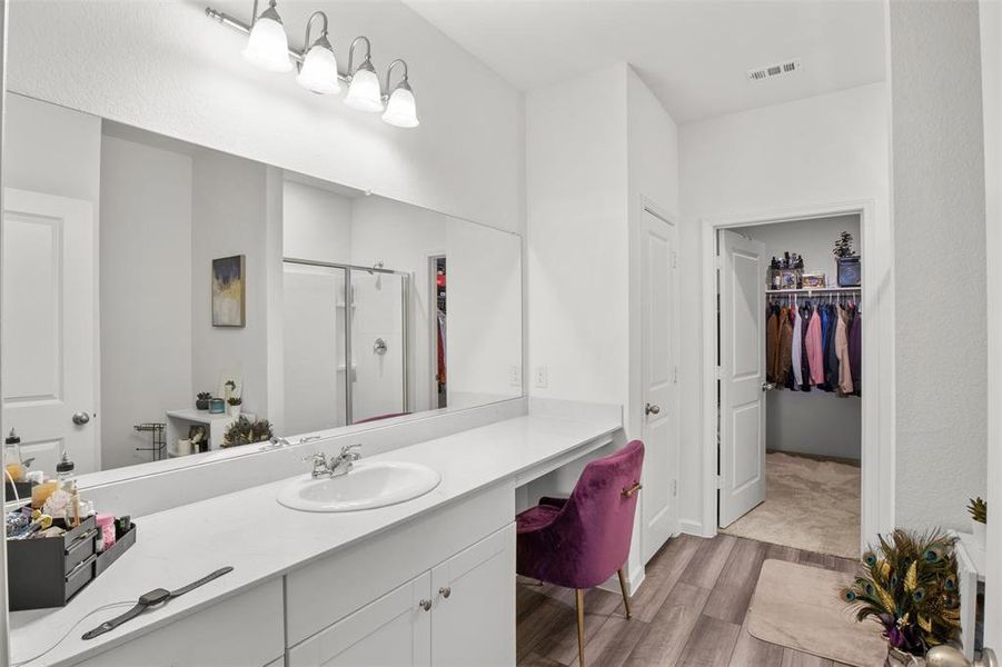 Bathroom with a shower stall, vanity, wood finished floors, and a spacious closet