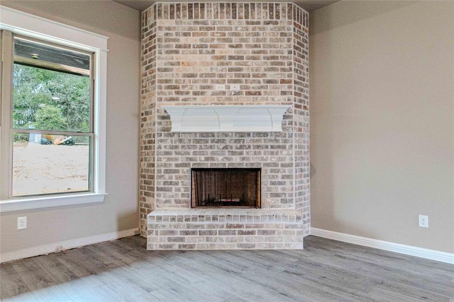 Unfurnished living room with hardwood / wood-style flooring, a wealth of natural light, and a fireplace