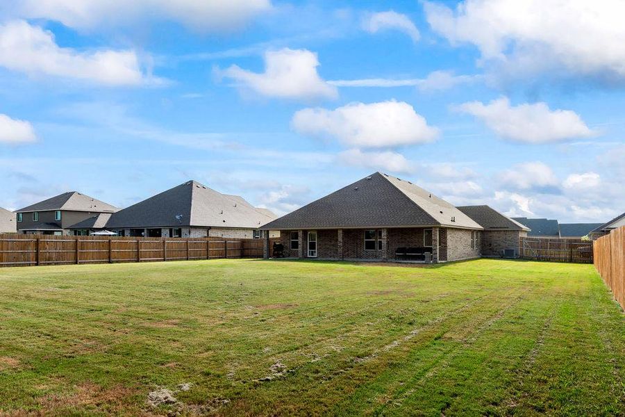 Back of property with a fenced backyard, a patio area, brick siding, and a shingled roof