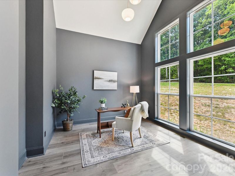 Light-filled office with soaring ceilings, dramatic floor-to-ceiling windows, and serene wooded views creating an inspiring workspace.