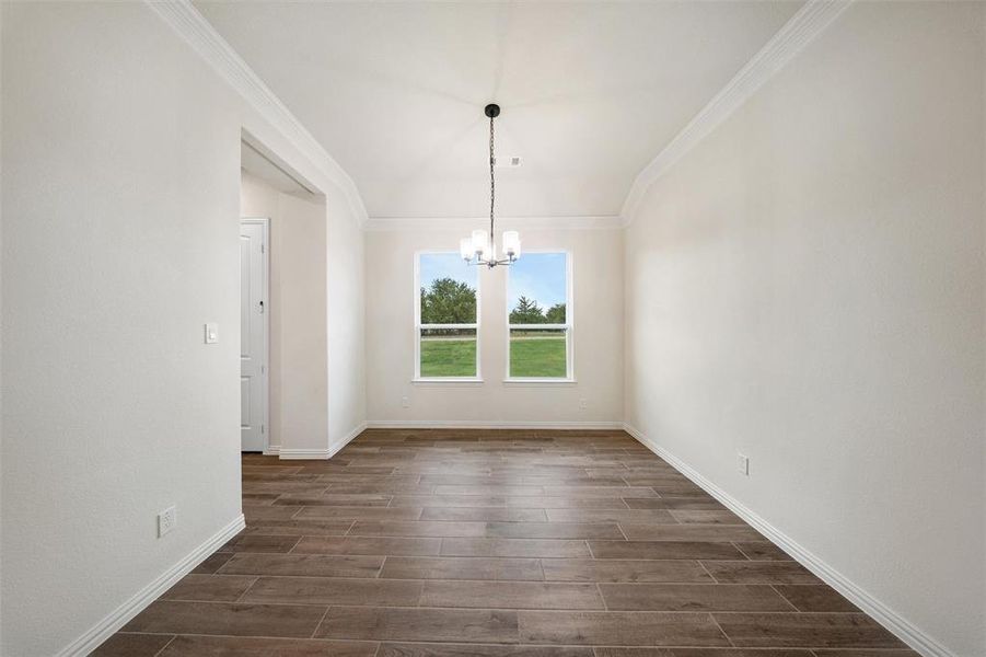 Unfurnished dining area featuring crown molding, a chandelier, and wood tiled floors