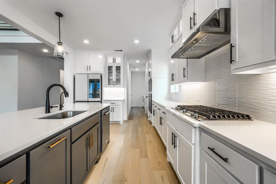 Kitchen featuring under cabinet range hood, light countertops, appliances with stainless steel finishes, white cabinetry, and a sink