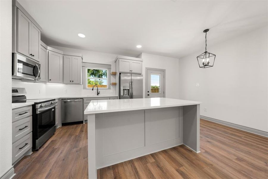 Kitchen featuring appliances with stainless steel finishes, recessed lighting, hanging light fixtures, dark wood finished floors, and gray cabinets