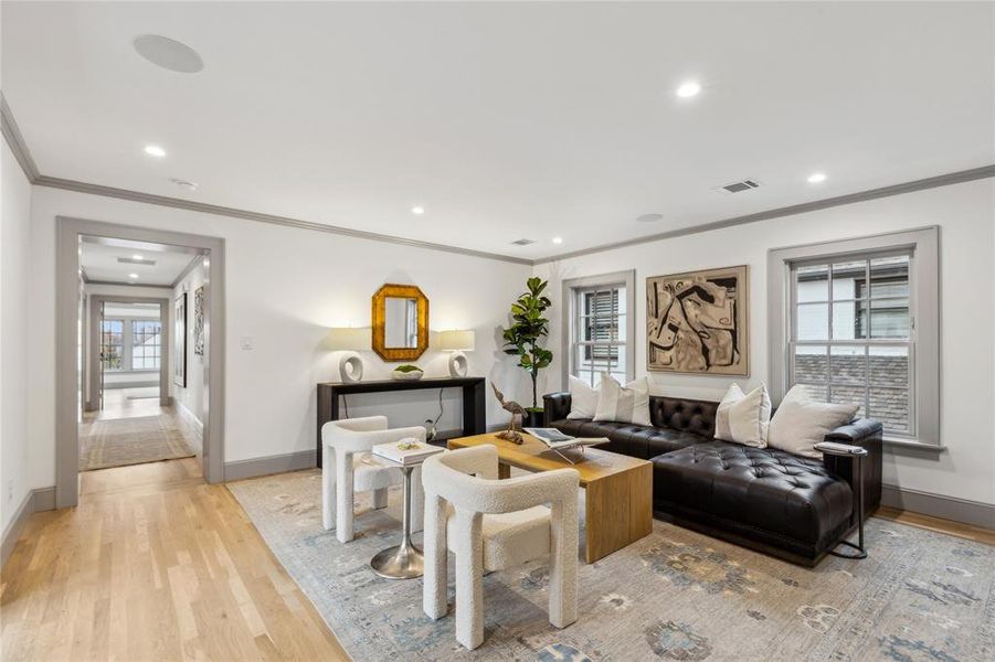 Living room with recessed lighting, visible vents, light wood-style floors, ornamental molding, and baseboards