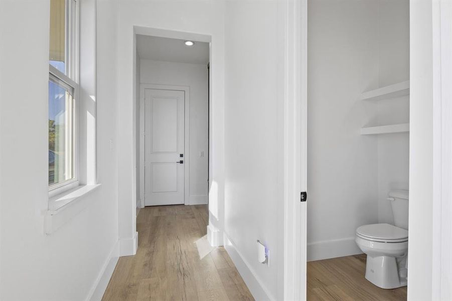 Bathroom with toilet, baseboards, wood finished floors, and built in shelves Bathroom with toilet, baseboards, wood finished floors, and built in shelves