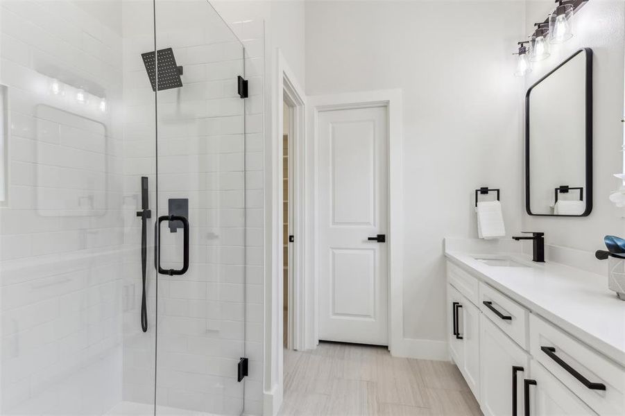 Bathroom featuring tile patterned flooring, walk in shower, and vanity