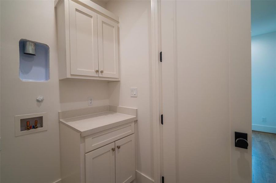 Clothes washing area featuring cabinets and hookup for a washing machine