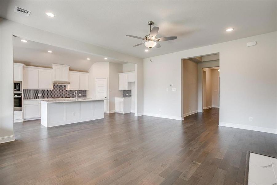 Unfurnished living room featuring ceiling fan, dark hardwood / wood-style floors, and sink