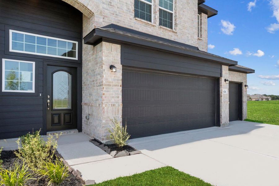 Inviting exterior entry with brick elevation, black trim accents, and neatly landscaped flower beds—creating a warm first impression.  Open the amazing custom door to your new CastleRock Community Home today!
