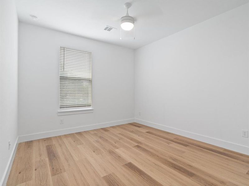 Empty room featuring ceiling fan, visible vents, baseboards, and light wood finished floors