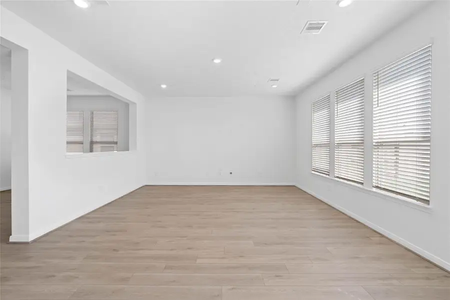 Expansive and open family room, designed for modern living and family togetherness! It features large windows with privacy blinds, gorgeous Layton Lake Soft Beige vinyl plank flooring, high ceilings, recessed lighting, and customer neutral paint.