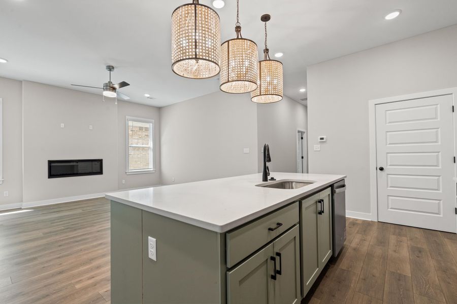 Kitchen featuring gray cabinetry, open floor plan, recessed lighting, a kitchen island with sink, and dark wood-type flooring
