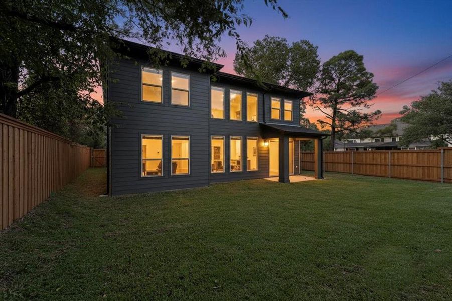 Back of house at dusk with a fenced backyard and a patio area