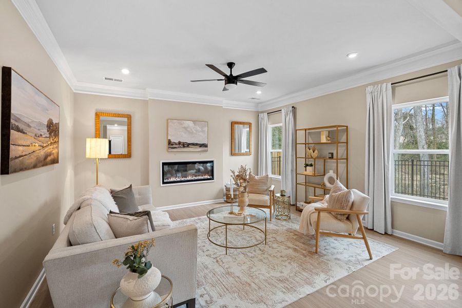 Cozy living room with crown molding, ceiling fan and electric fireplace. Cozy living room with crown molding, ceiling fan and electric fireplace.