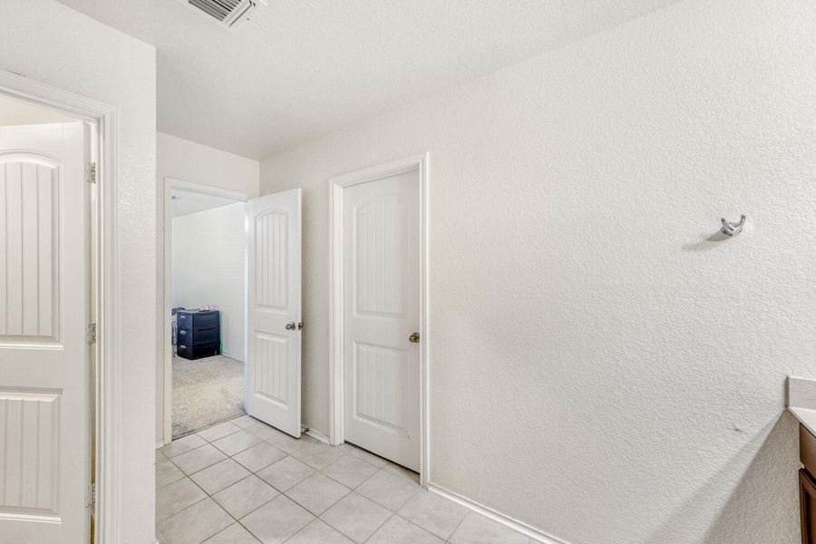 Hall with light tile patterned floors and a textured wall