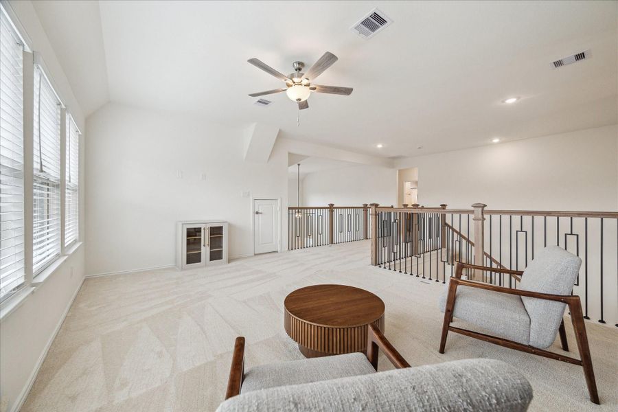 The open game room offers abundant natural light and versatile space, complete with soft carpet underfoot, ceiling fans, and recessed lighting for comfort and style.