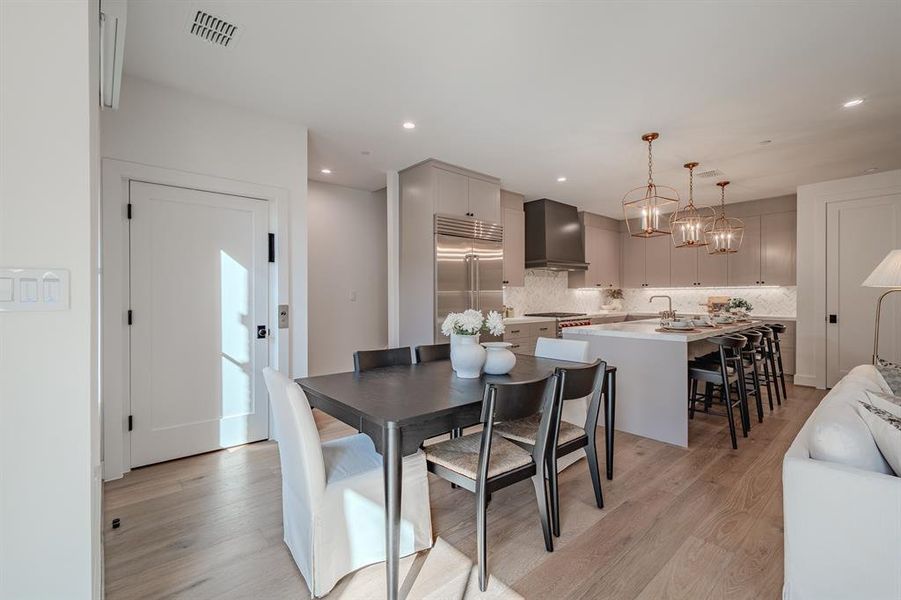 Dining room featuring light wood finished floors, a chandelier, and recessed lighting Dining room featuring light wood finished floors, a chandelier, and recessed lighting