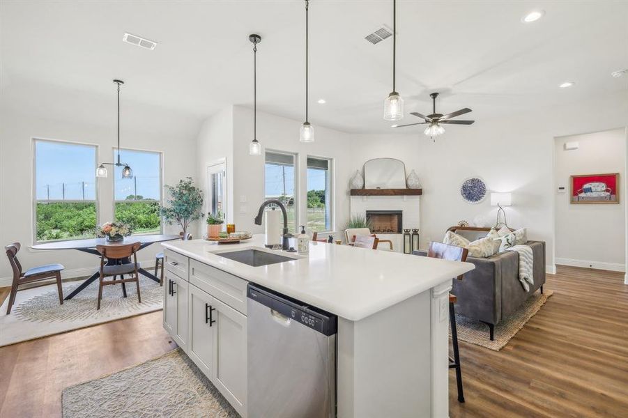 Kitchen featuring stainless steel dishwasher, sink, hardwood / wood-style flooring, and a center island with sink