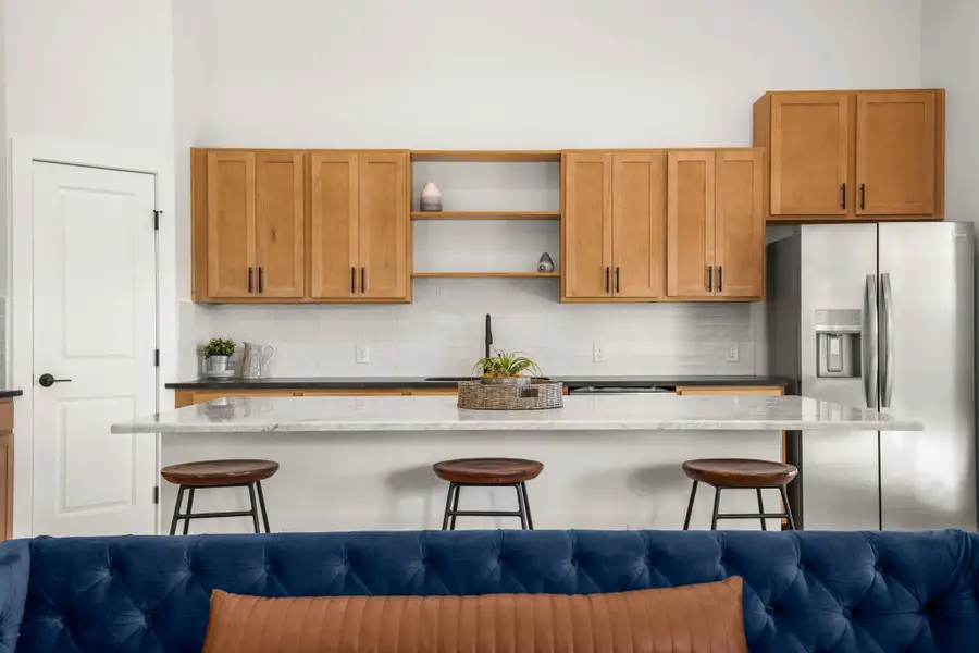 Kitchen featuring decorative backsplash, stainless steel fridge, dark stone counters, and open shelves