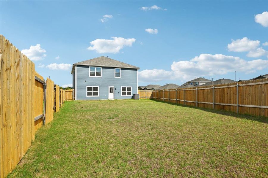 Back of property with a yard and central air condition unit