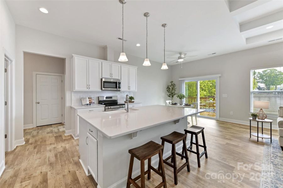 Kitchen features quartz counters, island with seating/storage, stainless steel appliances, tile back splash, upgraded lighting & breakfast area!