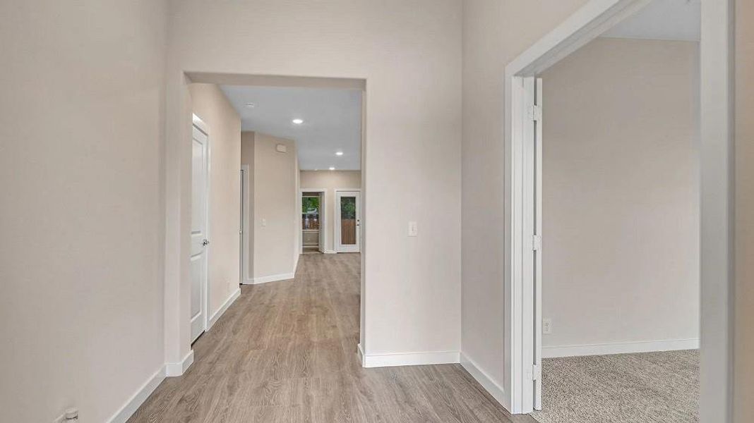 Hallway with wood finished floors, baseboards, and recessed lighting Hallway with wood finished floors, baseboards, and recessed lighting