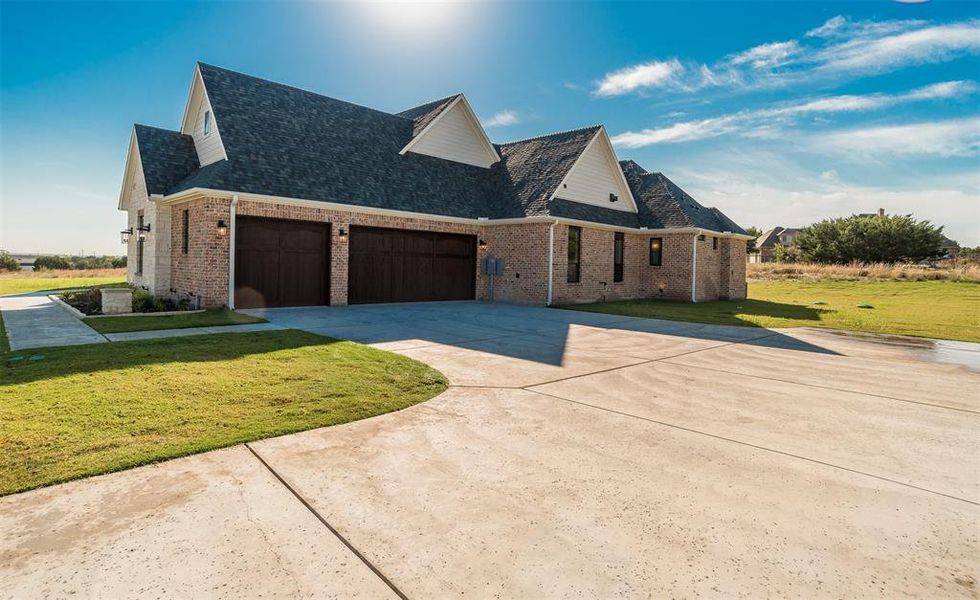 View of side of property with a lawn, brick siding, driveway, and a shingled roof
