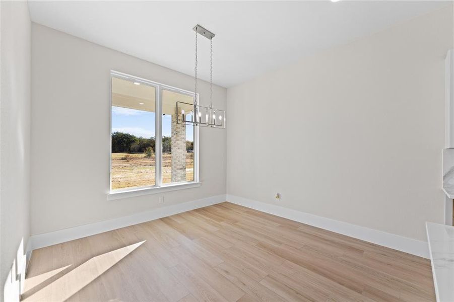 Unfurnished dining area featuring light wood-style flooring and a chandelier Unfurnished dining area featuring light wood-style flooring and a chandelier