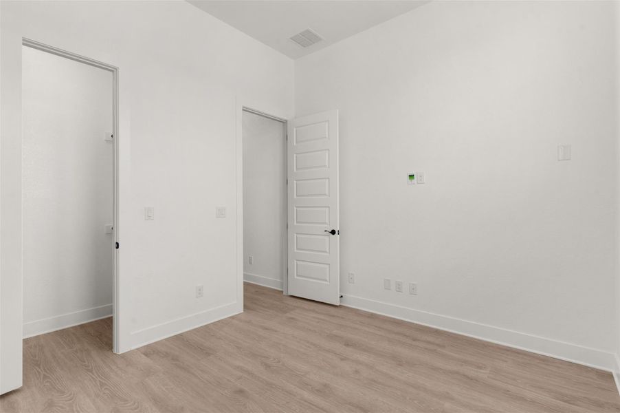 Unfurnished bedroom featuring light wood-type flooring and a walk in closet