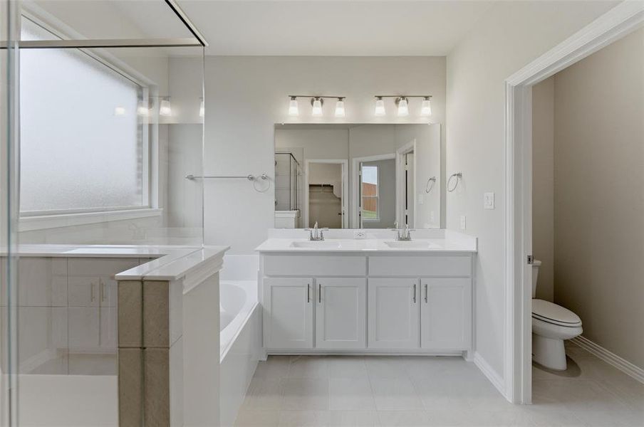 Bathroom featuring a dual vanity with white cabinetry and integrated sinks, a large mirror, and a three-light vanity fixture