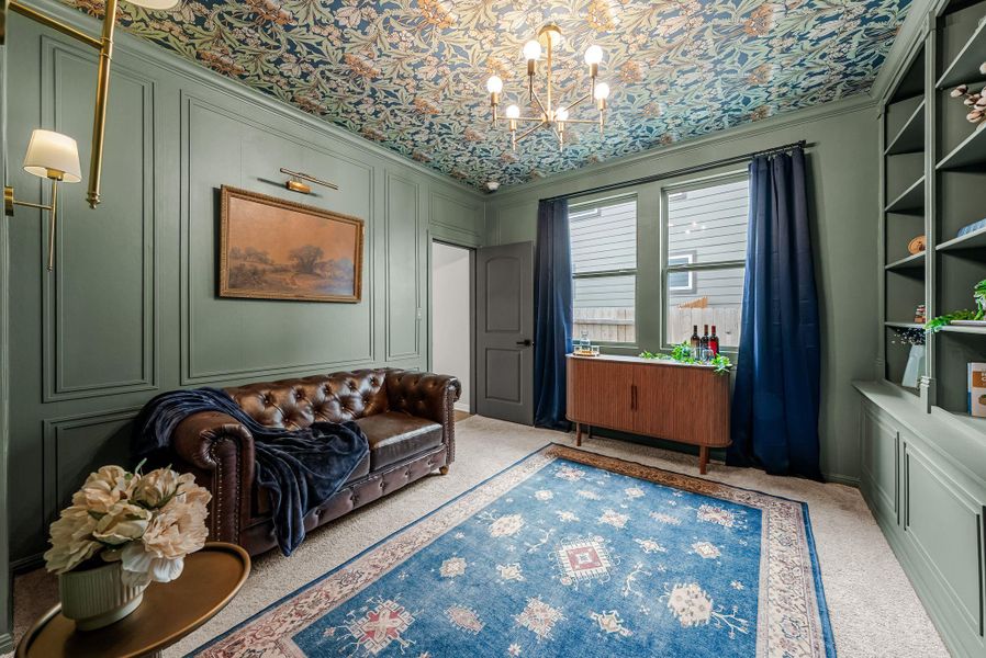 Sitting room featuring carpet floors, a decorative wall, crown molding, and suspended lighting